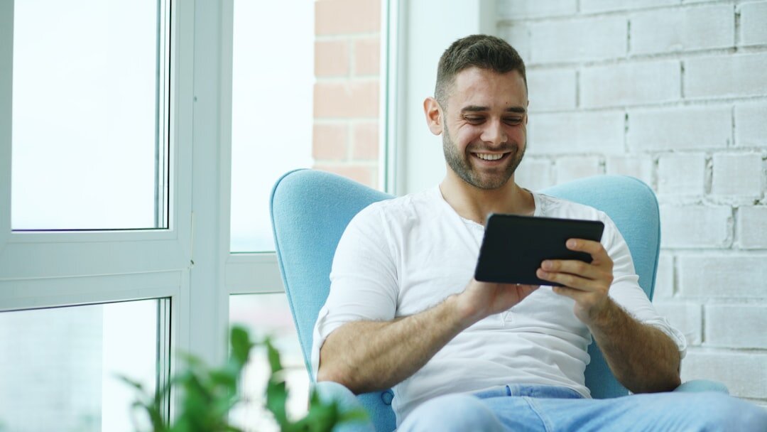 Brazilian man reading a book calmly at home by a window